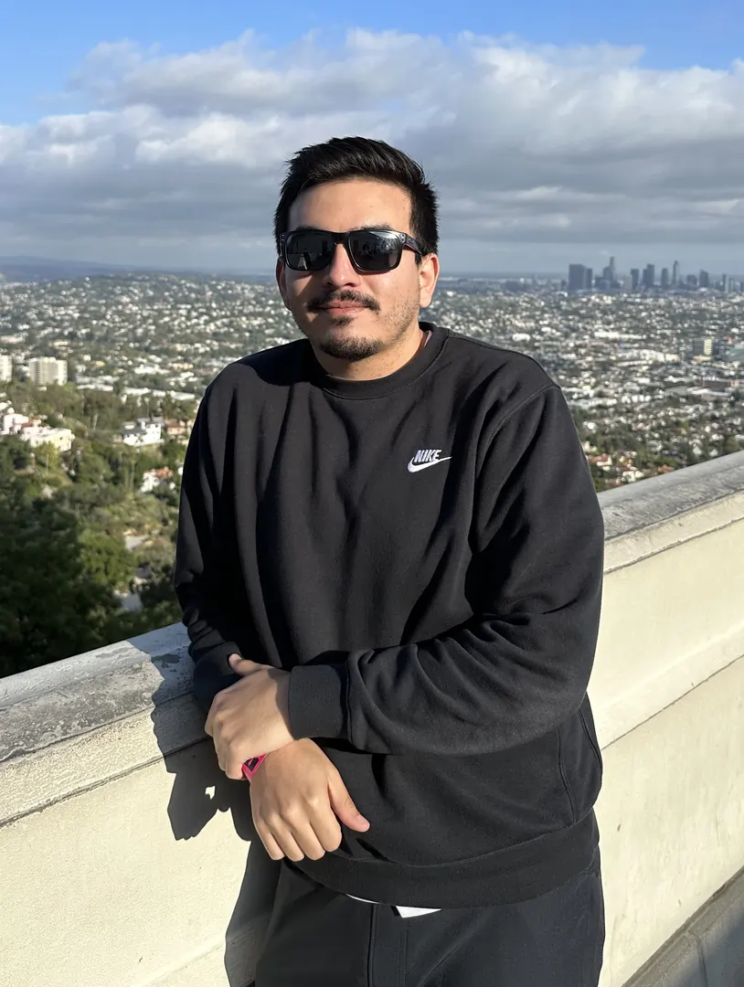 Johnny Parra leaning against a pony wall with los angeles in the background
